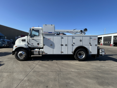 Service/utility truck side view showing multiple storage compartments, utility body, boom crane, and Mack MD7 cab.