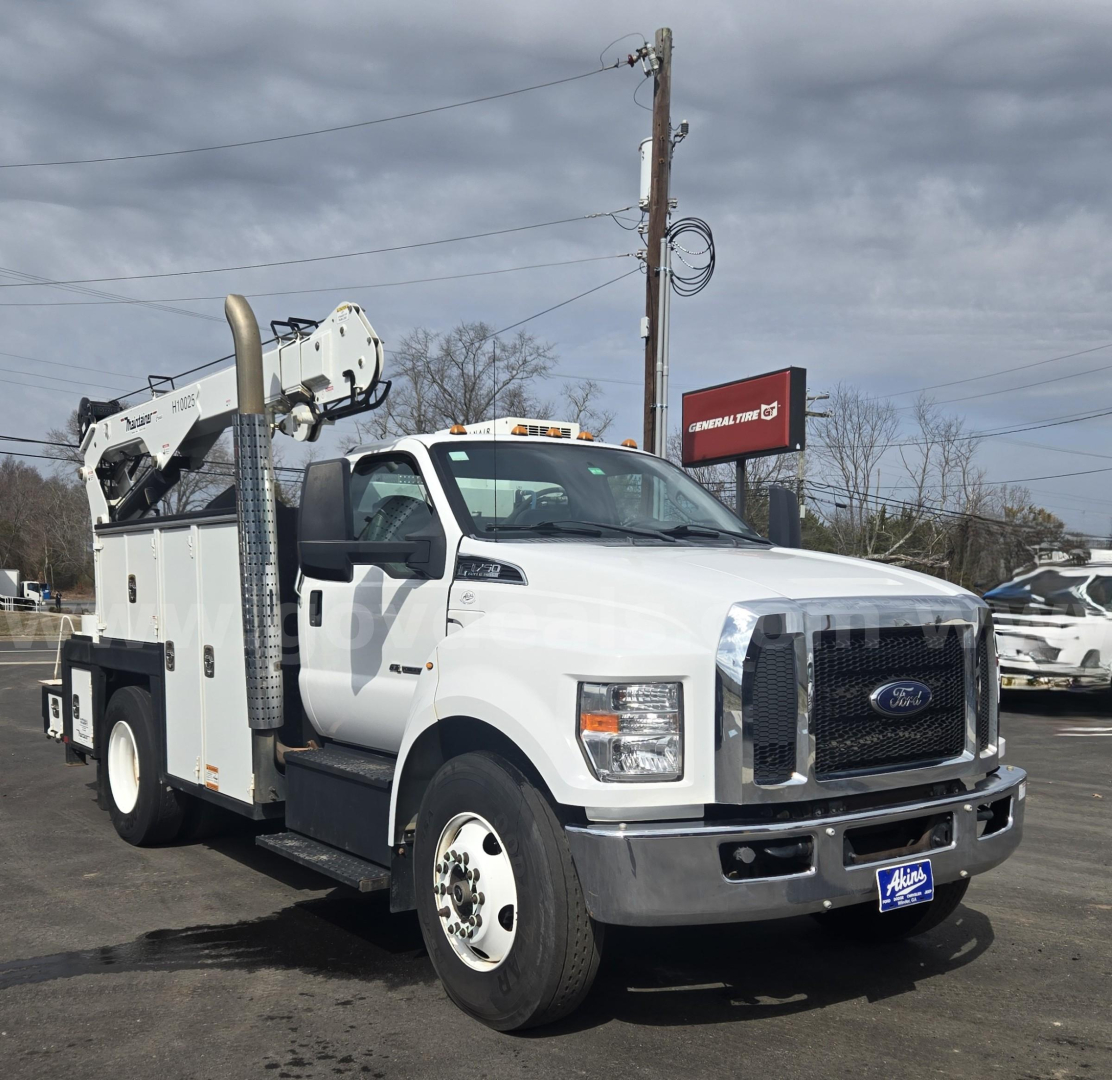 Ford F-750 service/utility truck showing boom lift and utility body with white cab and black grille