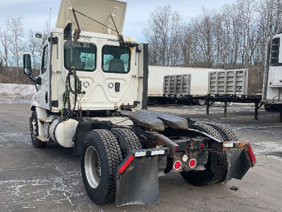 Truck rear view of a white Freightliner Cascadia daycab chassis showing fifth wheel and dual rear axles with mudflaps.