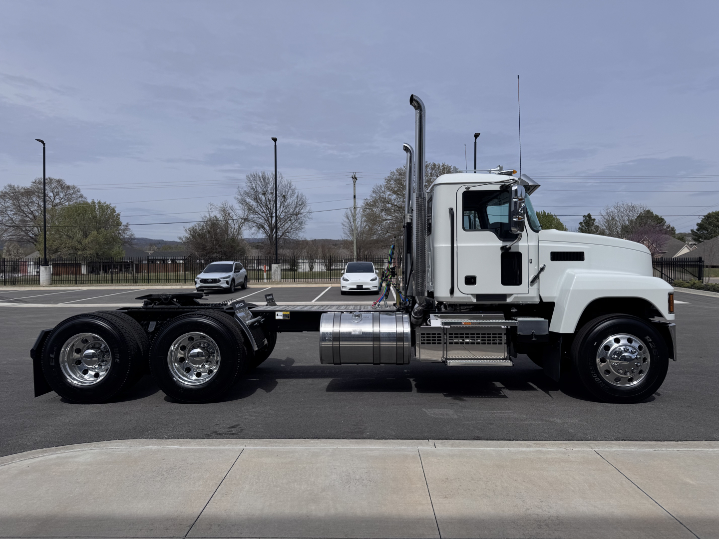 Semi truck chassis profile with white cab and dual rear axles, side view showing fuel tank and exhaust stack. No visible labels or placards.