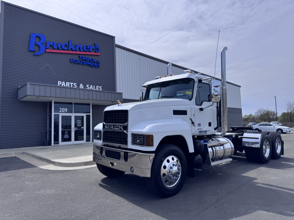 Mack PI64T truck in front of Bruckner's truck equipment building showing Daycab configuration and chrome exhaust stack.
