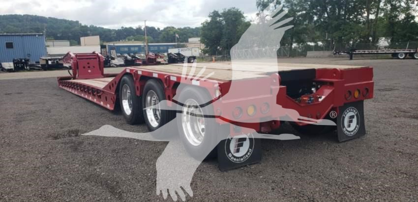 Fontaine 55 PVR Pro lowboy trailer with red frame and multiple axles, view showing side and rear with tires and stowed components.