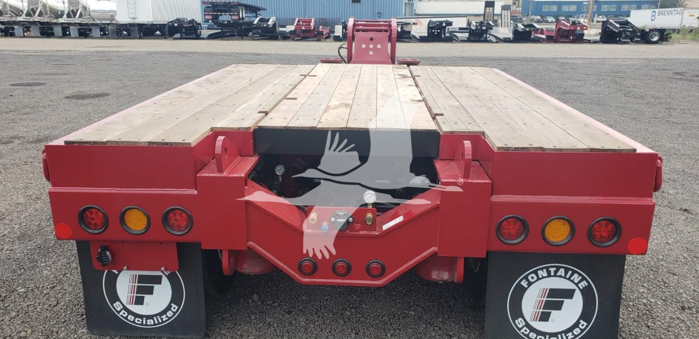 Trailer rear view showing Fontaine 55 Pvr Pro lowboy with wooden deck and red frames, rear lights, and black Fontaine wheel covers.