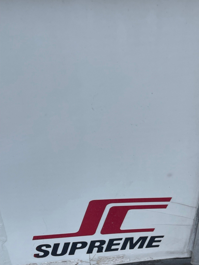 Image shows the lower corner of a vehicle with a Supreme JC logo on white body panel; no legible text about the truck specs visible.