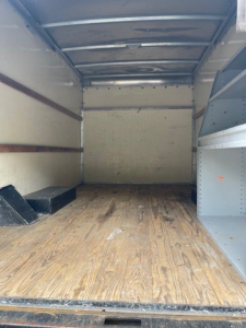 Truck cargo area with wooden floor and metal walls, empty interior of a 2014 Ford Econoline commercial cut van.