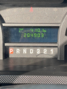 Dashboard showing odometer reading 208,903 miles and trip A 410.1 miles; gear indicator PRND321; image is a Ford Econoline commercial van interior dash.