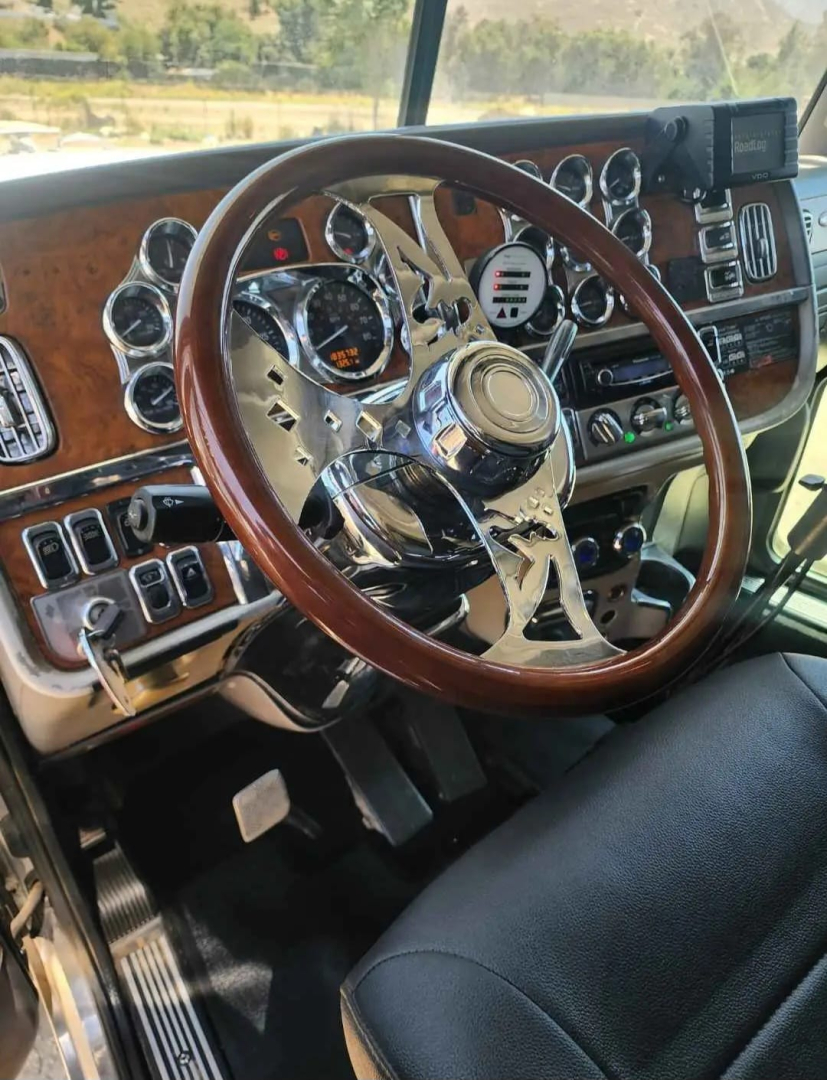 Peterbilt 379 truck interior steering wheel and dashboard with chrome gauges and wood grain accents.