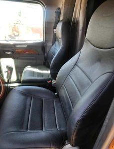 Peterbilt 379 interior seating view showing driver's seat and passenger seat with dark upholstery, door panel, and window.