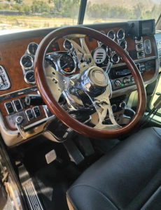 Peterbilt 379 truck interior steering wheel and dashboard with chrome gauges and wood grain accents.