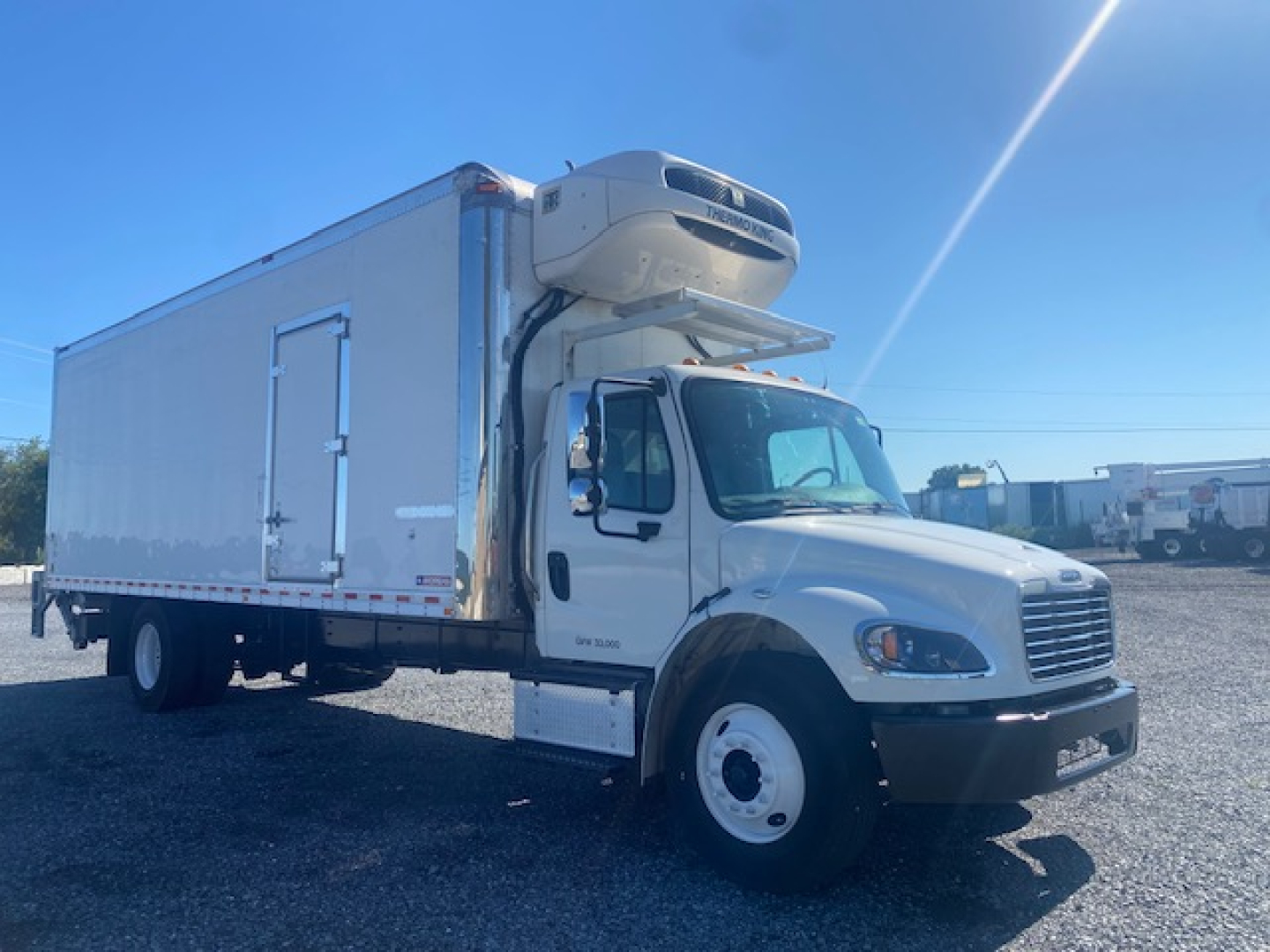 Freightliner M2 106 box truck with a refrigeration unit mounted on cab; white exterior; side view showing cooler