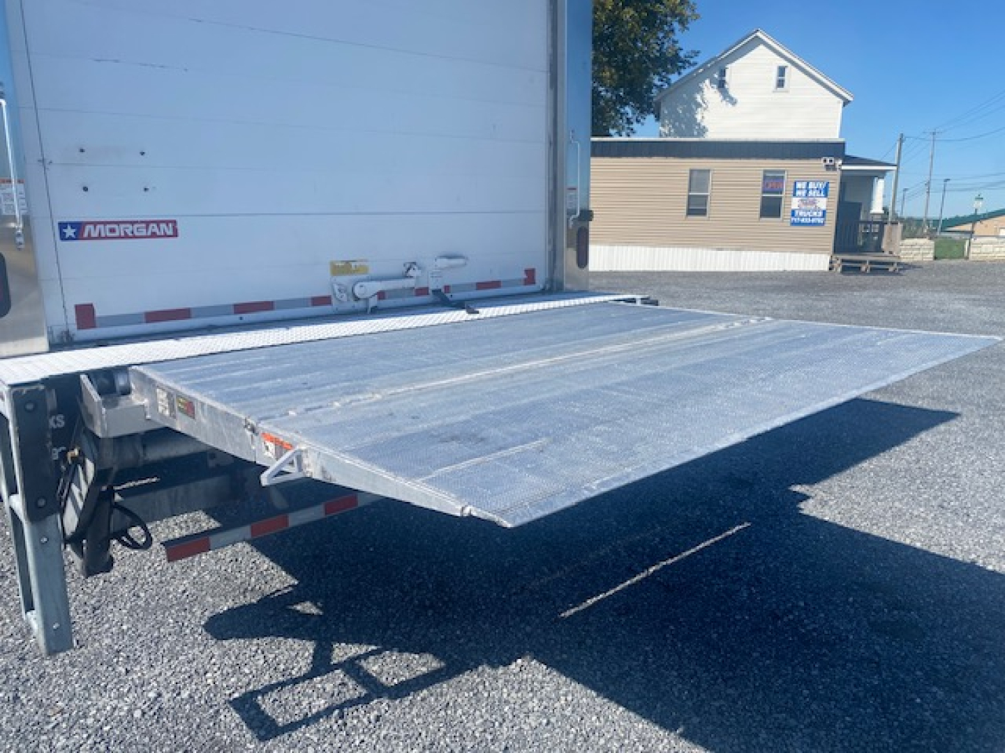 Flatbed ramp rear-view of a 2019 Freightliner M2 106 refrigerated truck with a fold-out aluminum ramp extended from the back of the trailer.