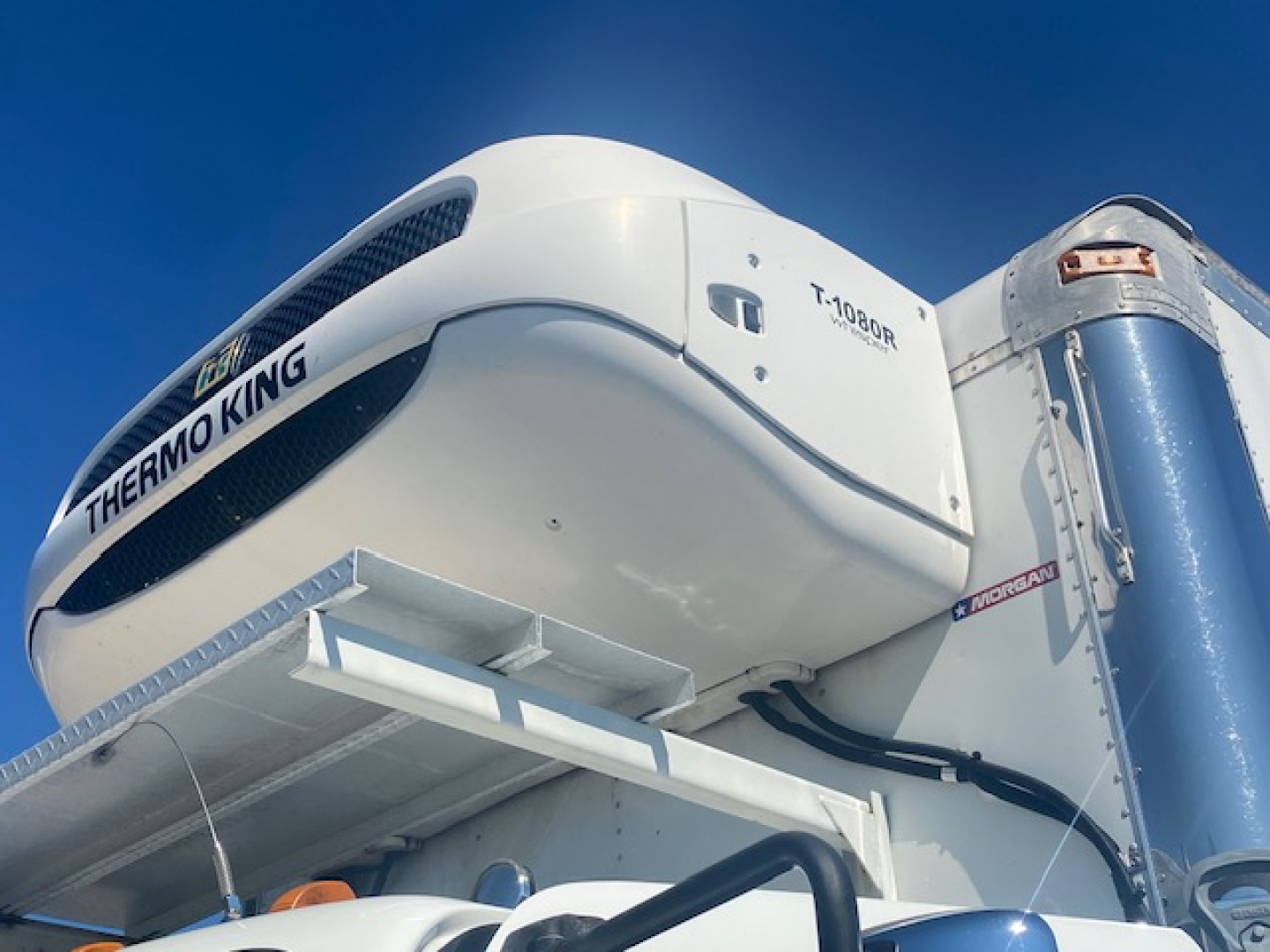 Refrigerated Freightliner M2 106 truck engine area showing Thermo King refrigeration unit and mounting components.