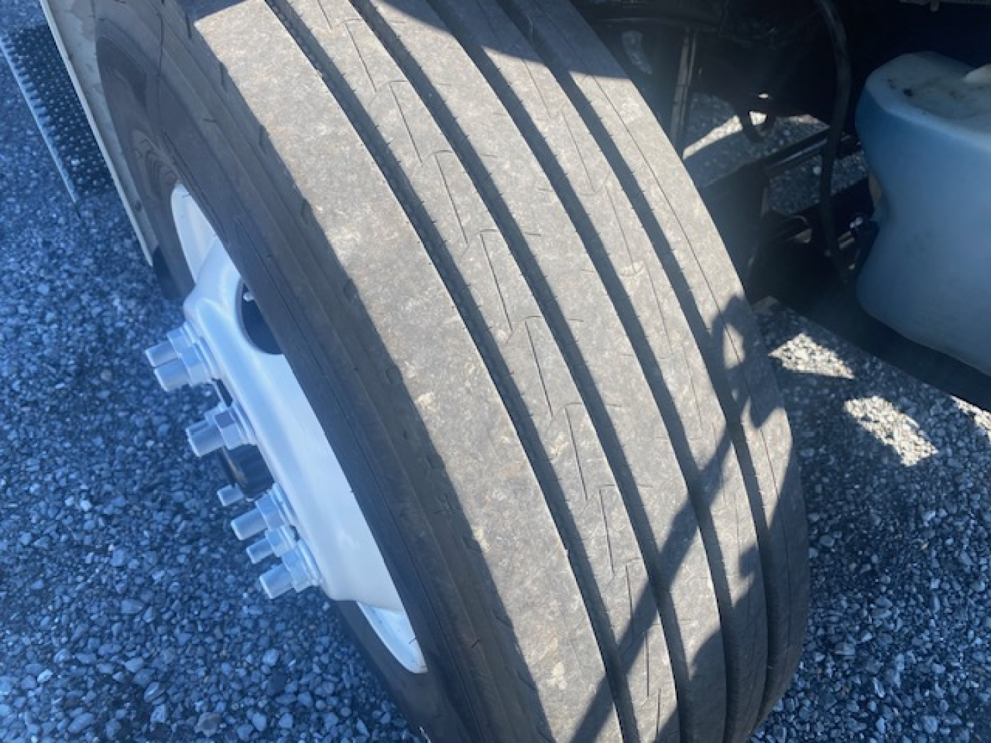 Freightliner M2 106 wheel and front tire visible in a refrigerated truck listing showing lug nuts and rim.