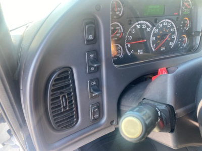 Freightliner M2 106 cabin interior view showing gauge cluster, steering wheel column, and driver-side dash controls.