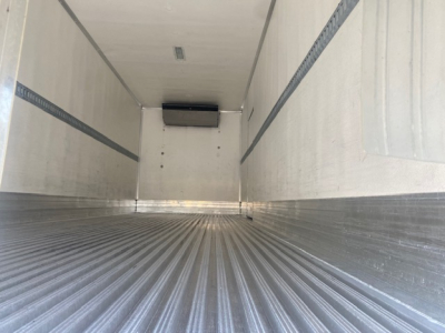 Interior of a refrigerated freight truck trailer showing ribbed metal floor and white insulated walls