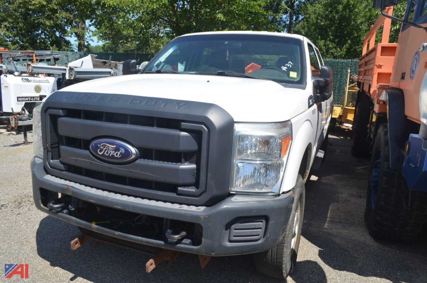Front view of a white 2012 Ford F-250 Super Duty pickup truck with black grille and bumper in a used vehicle lot.