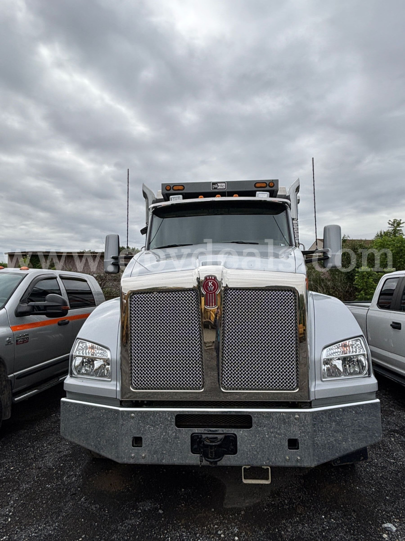Kenworth T880 dump truck front view showing large chrome grille with Kenworth emblem and bumper.