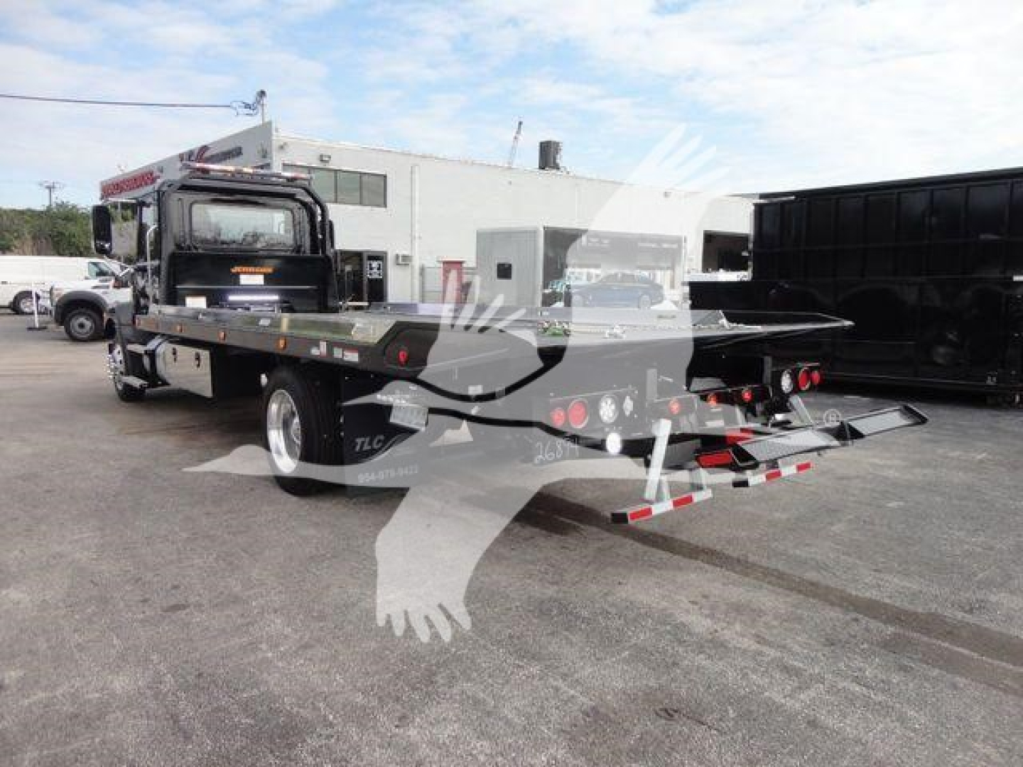 2027 Mack MD6 rollback truck rear view showing flatbed with tow equipment and taillights.