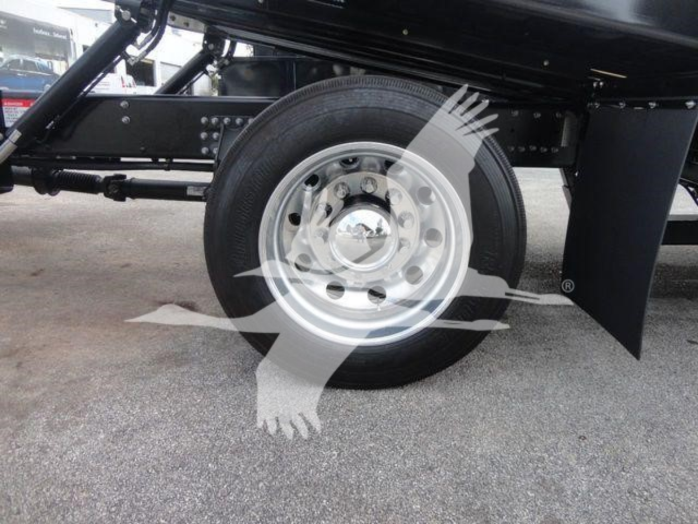 Wheel and undercarriage of a 2027 Mack MD6 rollback truck showing the steel wheel with hubcap, tire, and part of the suspension and frame.