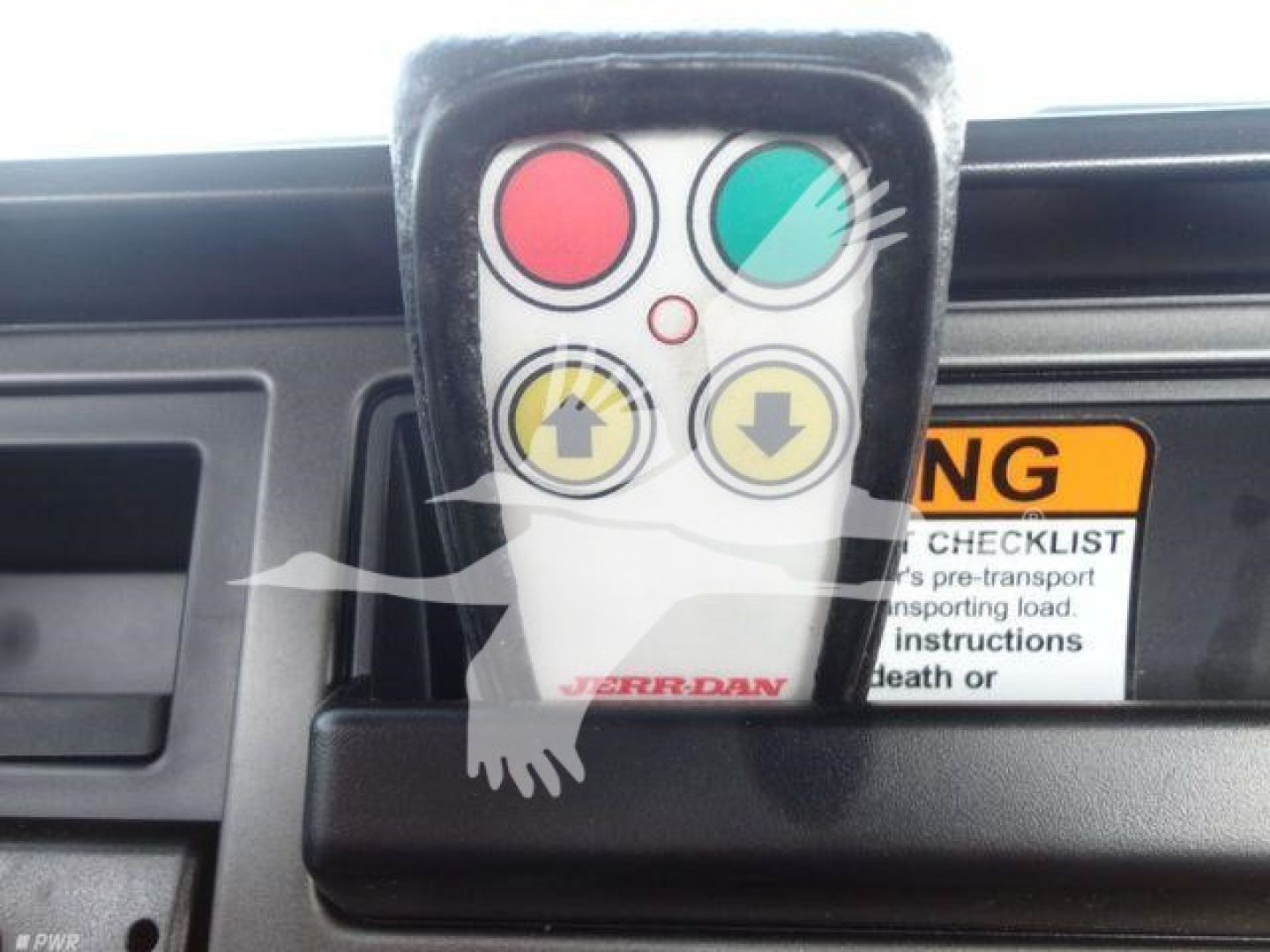 Remote control with red, green, and yellow buttons mounted in Mack MD6 dashboard area.