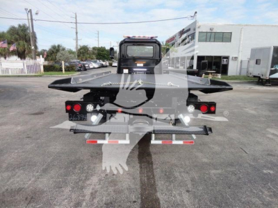 Back view of a new 2027 Mack MD6 rollback truck showing rear platform and taillights.