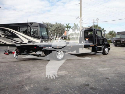 Truck showing rollback tow truck with flatbed and wrecker equipment; visible text includes J07254 stock number label and Mack MD6 chassis in background.