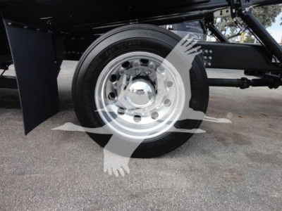 Wheel and part of chassis of a Mack MD6 rollback truck with chrome hubcap and black tire, reflective image watermark across center.
