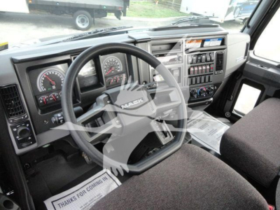 Cab interior of a Mack MD6 truck showing steering wheel, dashboard gauges, and center console with controls.