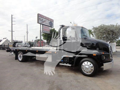 2027 Mack MD6 rollback truck with flatbed in service lot showing cab and towing bed.
