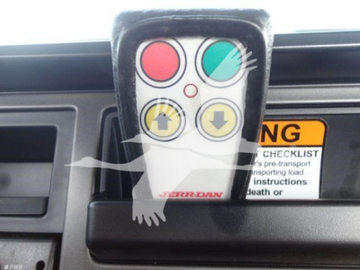 Remote control with red, green, and yellow buttons mounted in Mack MD6 dashboard area.