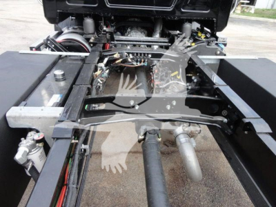 Chassis view of a 2027 Mack MD6 rollback truck showing the fifth wheel area and dual exhaust pipes with visible hydraulic lines and frame rails.