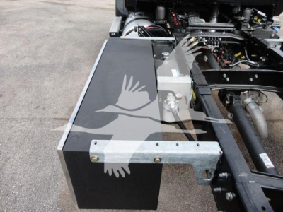MD6 truck component bay showing metal toolbox and hydraulic lines with frame rail and wiring visible.