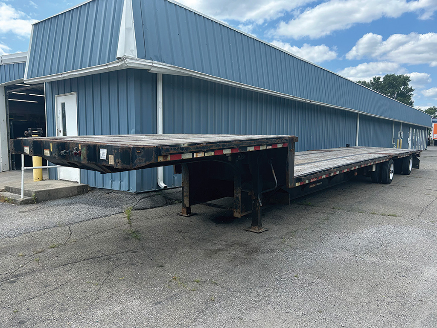Great Dane Freedom SE drop deck trailer in serviceable condition showing long flatbed with ramps folded at front and dual rear axles.
