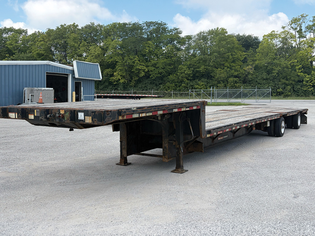 2018 Great Dane Freedom SE drop deck trailer showing long flatbed with multiple axles and undercarriage, storage box, and surrounding lot.