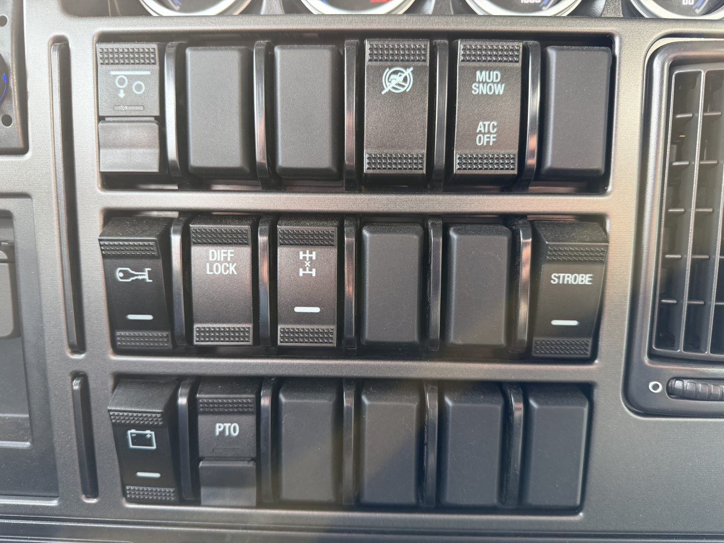 Dashboard switches and controls panel of a 2027 Mack GR84F dump truck showing various toggle switches and labels such as DIFF LOCK, MUD SNOW, ATC OFF, STROBE, PTO, and other blank rocker switches.