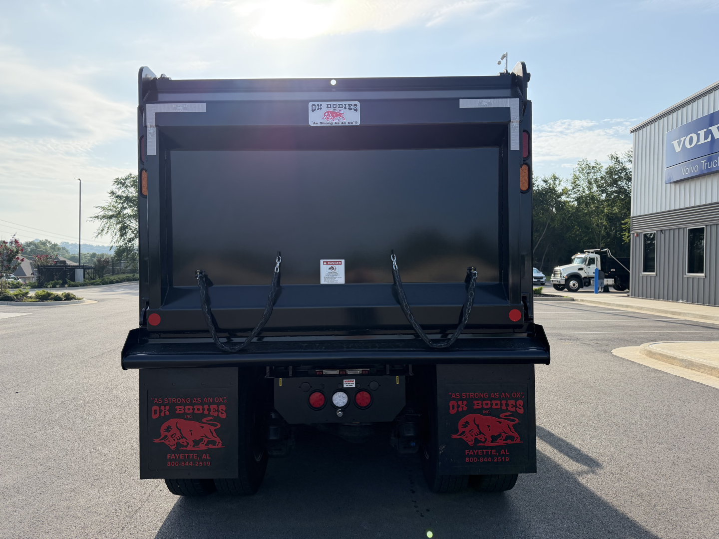 Mack GR84F dump truck rear showing tailgate and mud flaps with warning decals and rear lights.