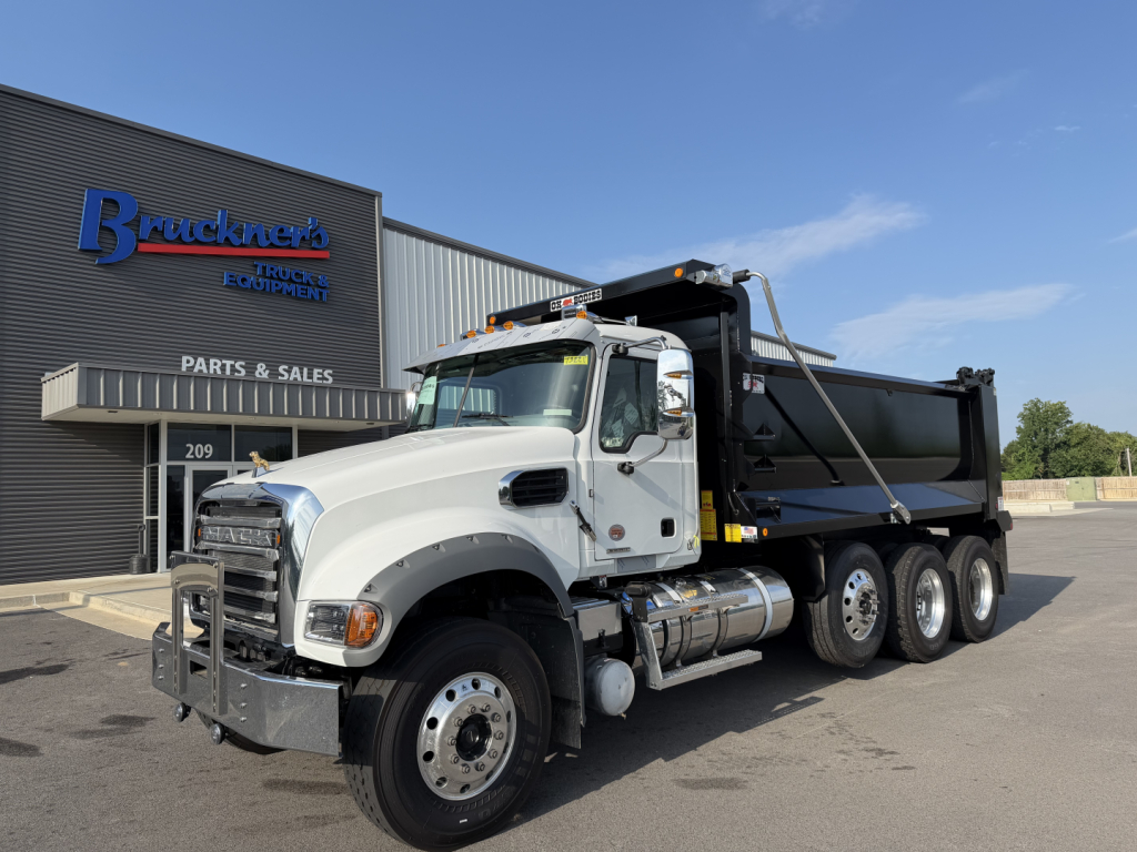 Dump truck image showing Mack GR84F dump truck in front of dealership with stock number 73221 and VIN 1M2GR4NCXVM010285.