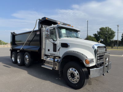 Dump truck showing Mack GR84F split-axle with aluminum cab, large front bumper, steel dump bed, and side steps; VIN 1M2GR4NCXVM010285 visible on listing.