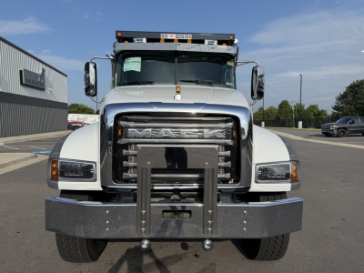 Truck front view of a white 2027 Mack GR84F dump truck with large grille, bumper guard, and towing hitch, displaying Mack emblem on grille.