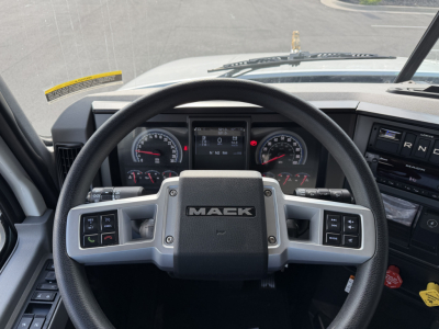 Mack GR84F truck interior view showing steering wheel with Mack logo and dashboard gauges.