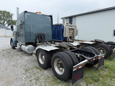 Peterbilt 389 UltraCab truck tractor left-side rear view showing fifth wheel and dual rear axles with mud flaps and fuel tanks.
