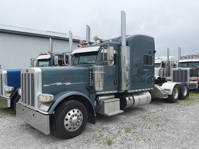 Peterbilt 389 UltraCab conventional sleeper truck showing front grille, dual vertical exhaust stacks, chrome bumper, and teal paint.