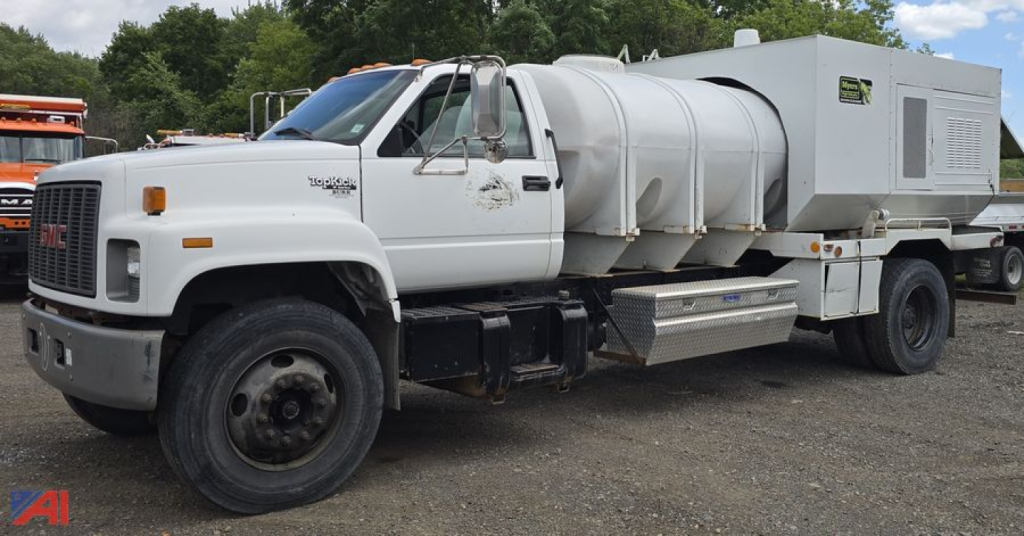 GMC TopKick C7500 tank utility truck with large stainless steel tank and utility box on the bed, front left view