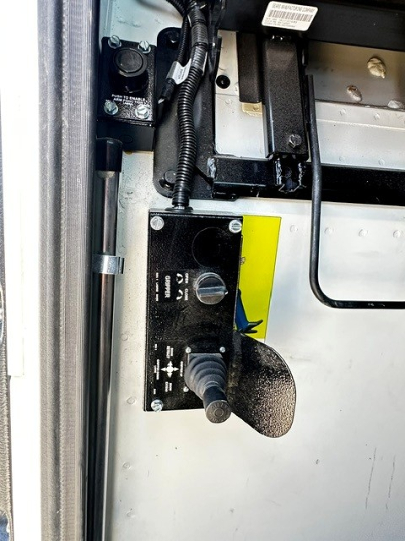 Fleet equipment close-up showing control panel with switches and hoses mounted on metal surface inside a truck cab area.