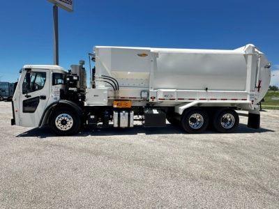 Side view of a new white 2025 Mack LR64 garbage truck with a large rear waste body and three axles, cab at left, VIN 1M2LR2GC2SM009854 visible in listing.