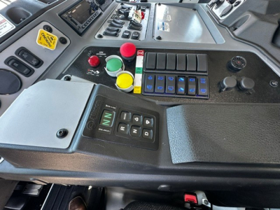 Cab control panel with colored push buttons and gear selector in a Mack LR64 truck cab, showing various switches and a digital display.
