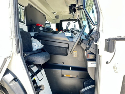 Cab interior of a 2025 Mack LR64 trucks showing steering wheel, dashboard, and seating area with displays.