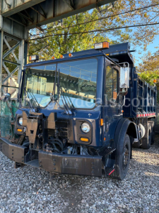 Dump truck cab in-service showing Mack MRU600 front with large bumper and dual headlights, windshield, mirrors, amber running lights, and heavy-duty grille.