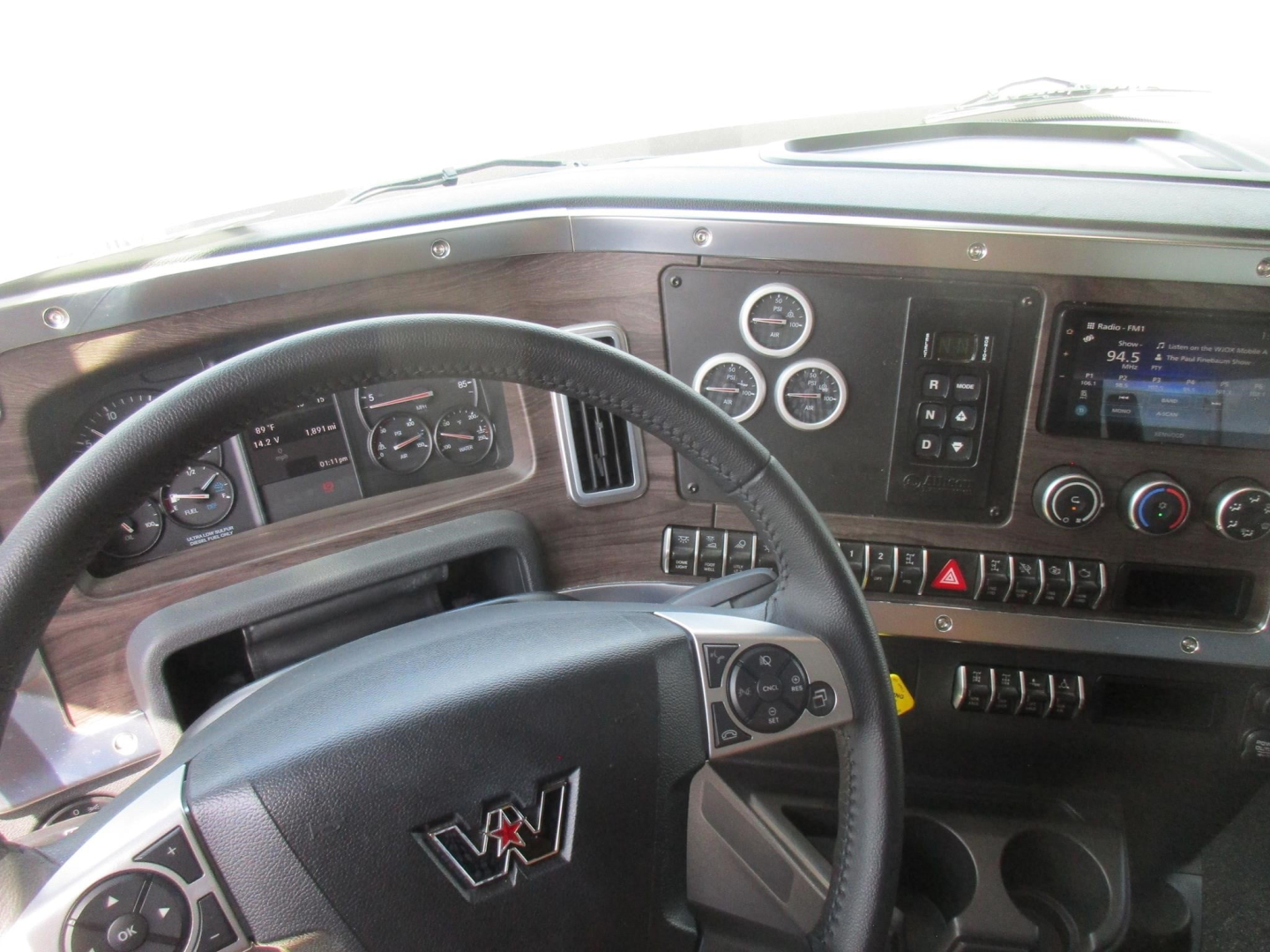 Western Star 49X truck cockpit showing steering wheel, dashboard gauges, and control panel with wood-grain trim.