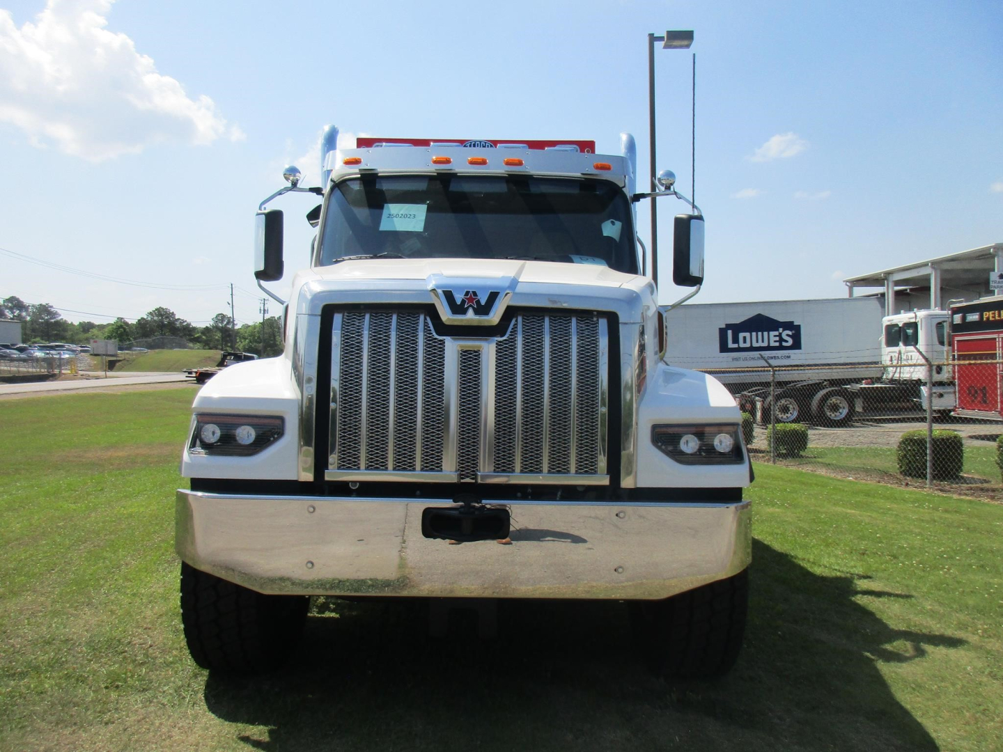 Front view of a white 2026 Western Star 49X dump truck with chrome grille, large bumper, and bold headlights.